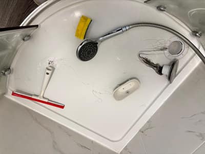 Shower tray with the shower head and cleaning tools mid-clean