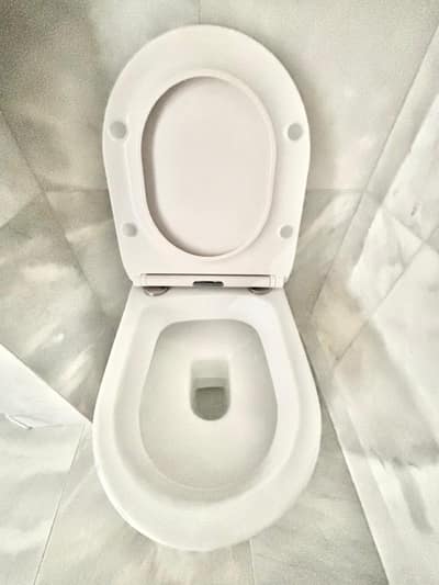 Clean white toilet on a marble-effect floor
