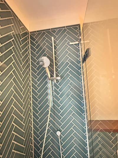 Shower with teal herringbone tiles and a clean glass screen