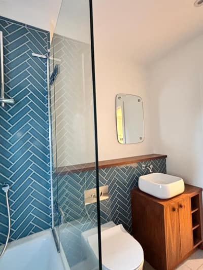 Spotless newly renovated bathroom with teal tiles, basin and wooden cabinet