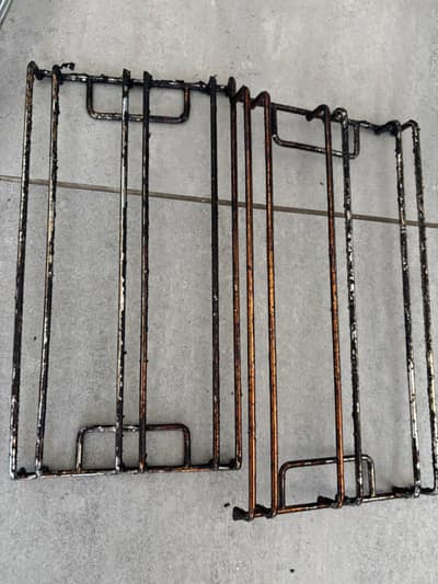 Oven shelf runners covered in burnt-on grease before cleaning