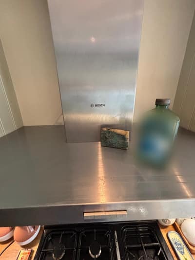 Stainless steel cooker hood being cleaned, with cleaning products