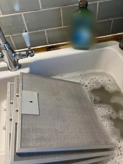 Cooker hood filters soaking in hot soapy water