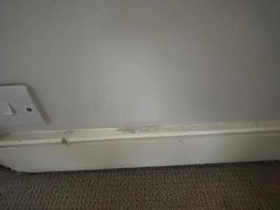 Skirting board beside a light switch before cleaning