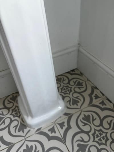 Basin pedestal and skirting on patterned floor tiles