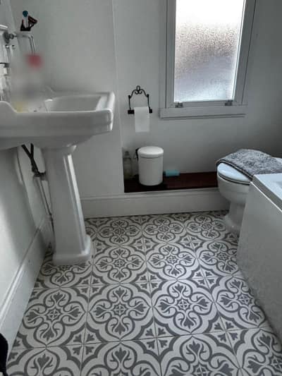 Clean bathroom with a pedestal basin and patterned floor tiles