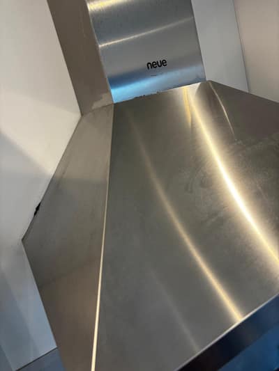 Side view of a polished stainless steel cooker hood